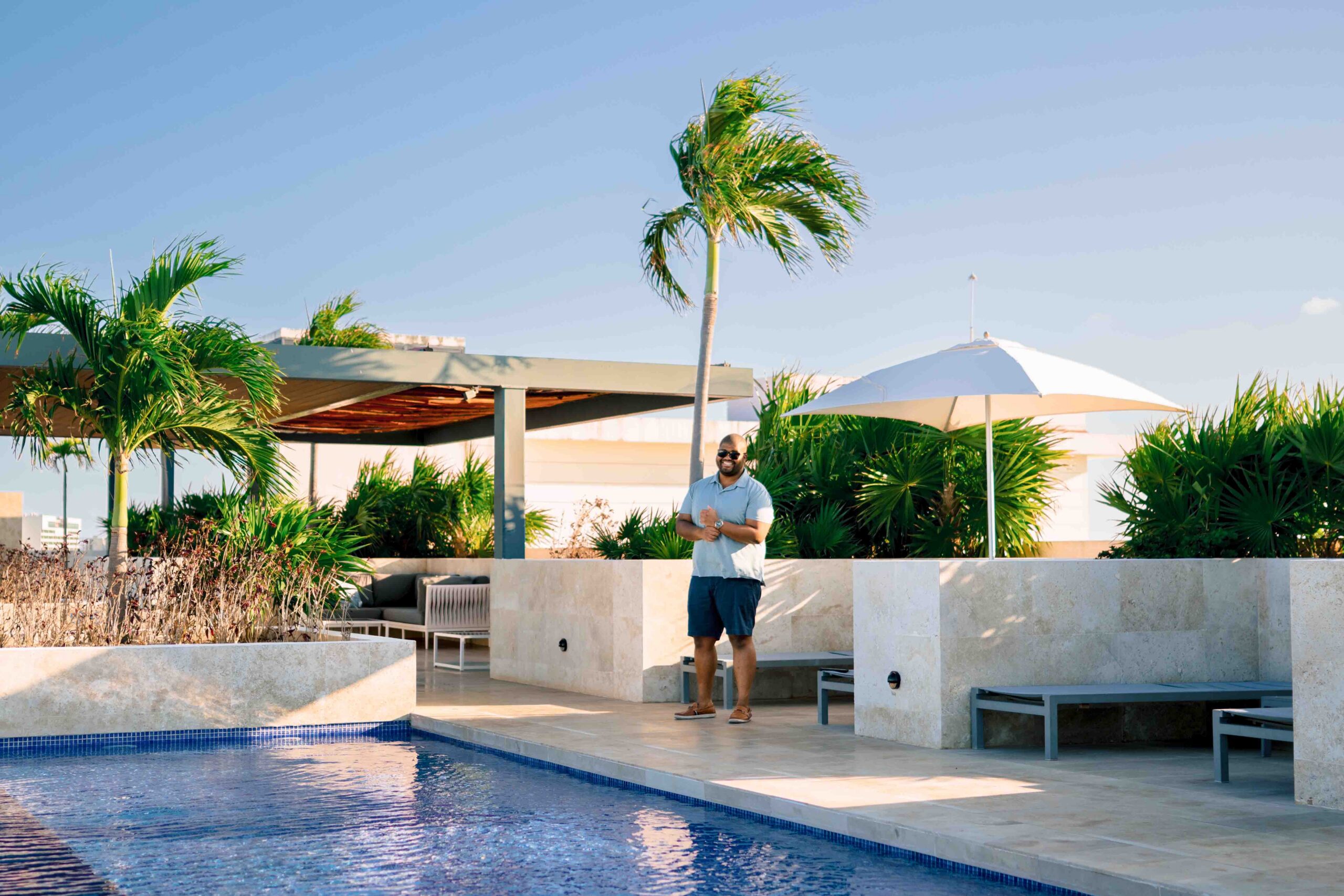 Sidney Baker-Green standing beside a pool surrounded by palm trees in Mexico